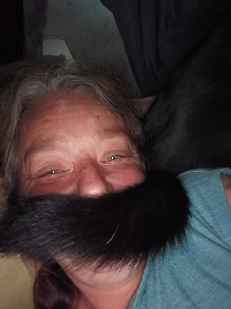 an adult female with a black dogs tail under her nose looking like a mustache.